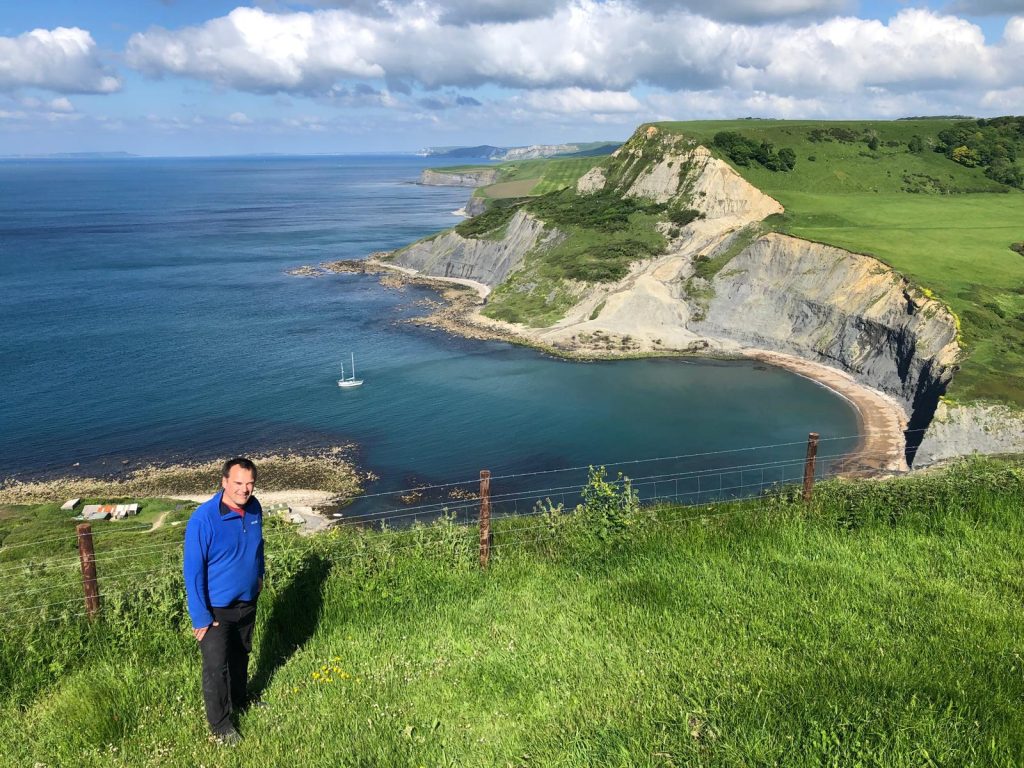 Looking west from a grassy cliff top path above Larksong anchored at the entrance to Chapmans pool